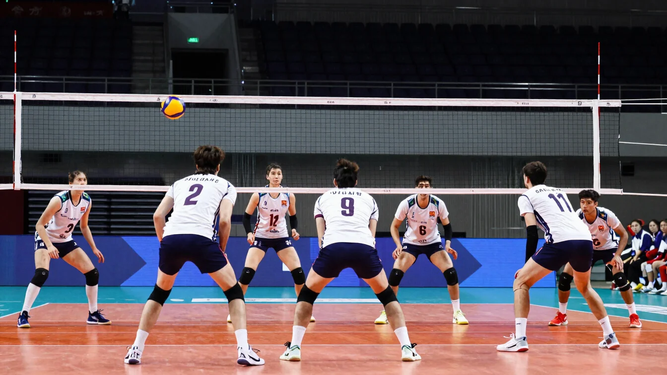 Volleyball players in a defensive stance during an indoor match,